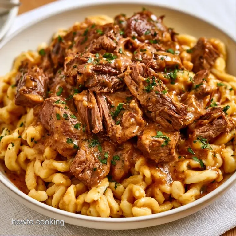 Tender beef strips in a glossy cream sauce served over buttery golden noodles in a minimalist ceramic white bowl.